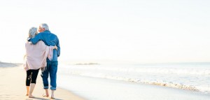 Retired couple walking on beach_1